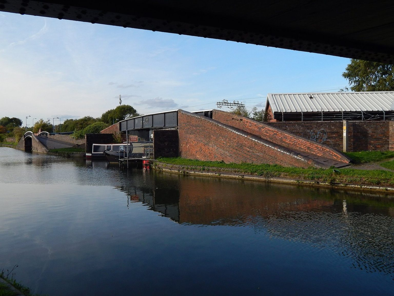 The New Main Line canal in Birmingham, with narrowboats moored beside brick bridges