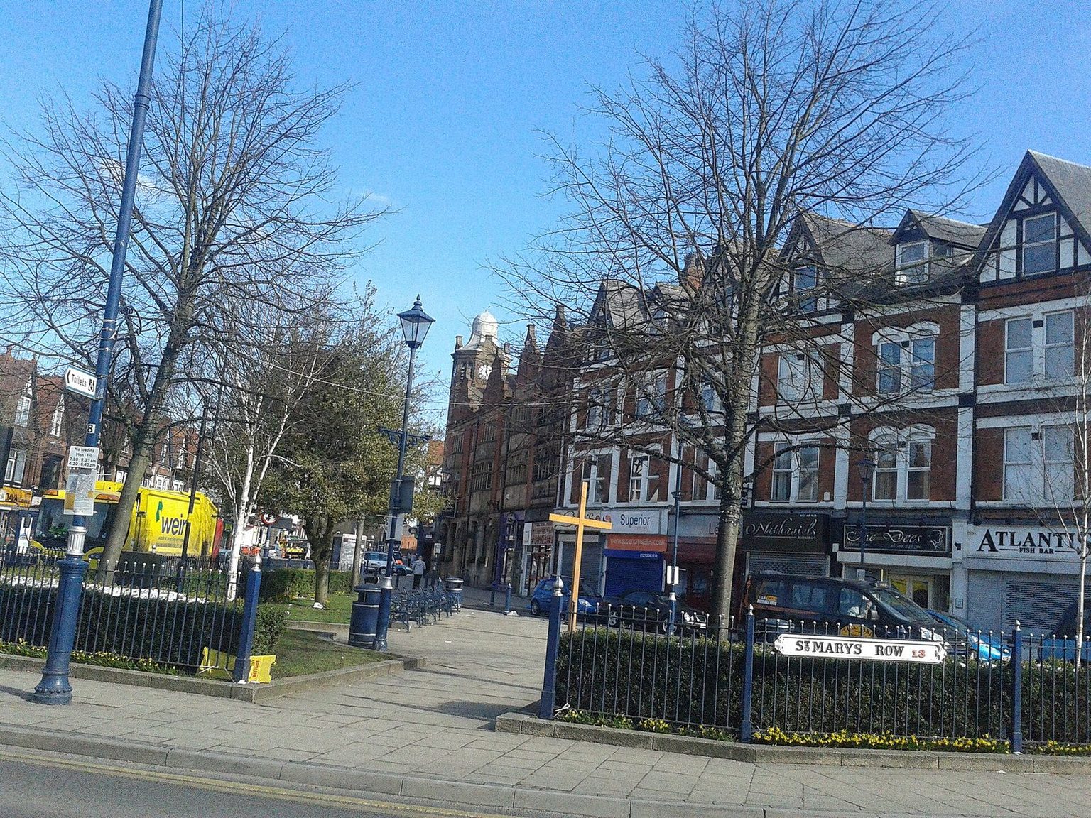 Shops and the village green railings at the St Mary's Row junction in Moseley