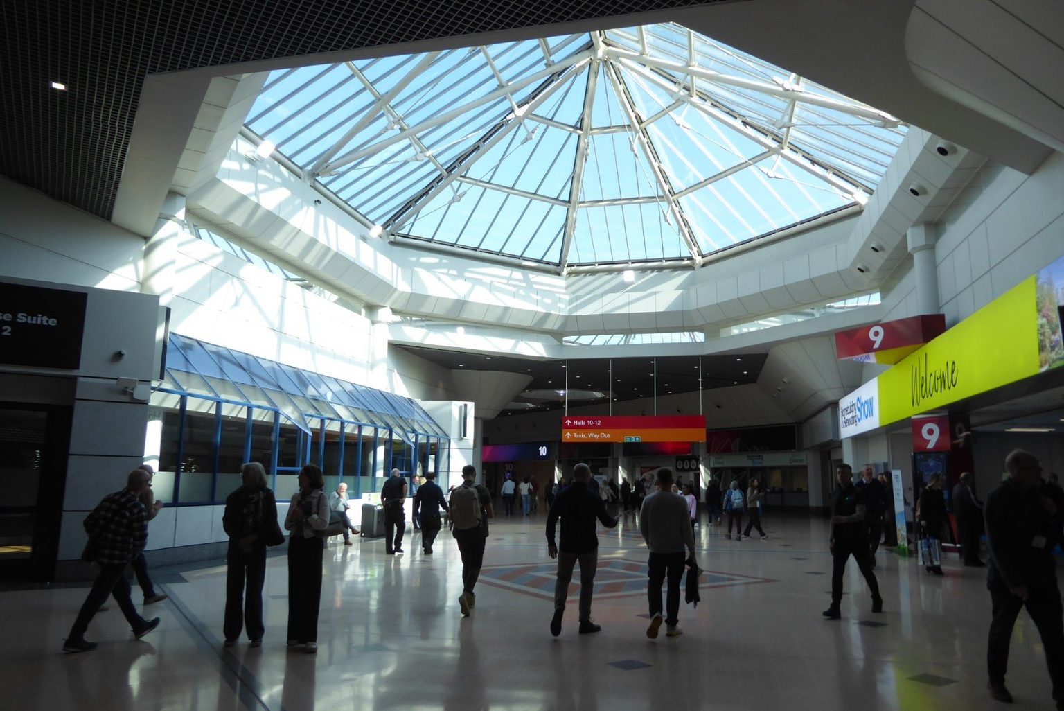 The concourse of the National Exhibition Centre under its glazed roof, with visitors crossing it