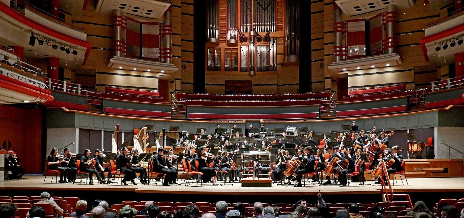 An orchestra on the platform of Symphony Hall, Birmingham, beneath the organ